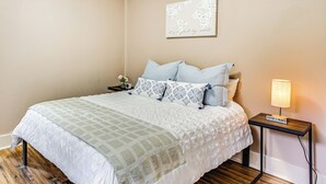 A neatly made bed with a patterned bedspread and pillows, a small bedside table with a lamp, and a world map artwork on the wall. - Mt Rainier Retreat 7 Mi to Park Entrance! (Ashford)