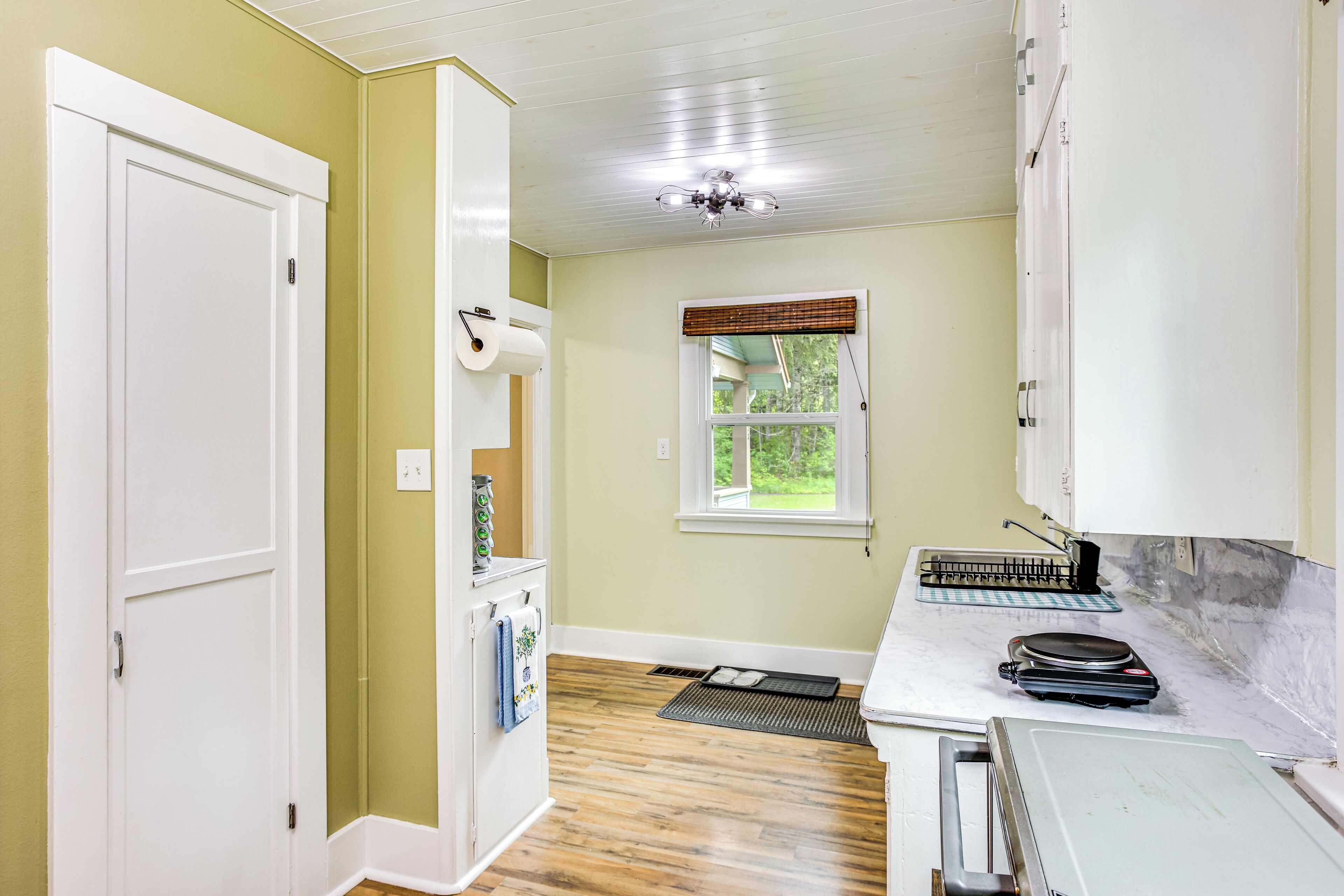 A kitchen with a refrigerator, a window with a view, a ceiling fan, and a countertop with a microwave.