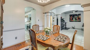 A dining area with a wooden table, four chairs, and a chandelier.