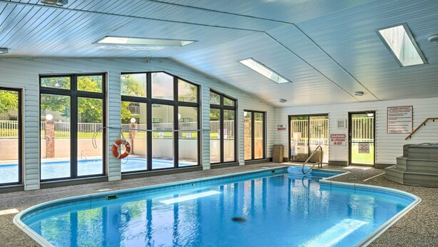 An indoor swimming pool with clear glass windows, a lifeguard stand, and a no lifeguard warning sign. - 1 Mi to 76 Strip: Family Condo in Branson! (Branson)