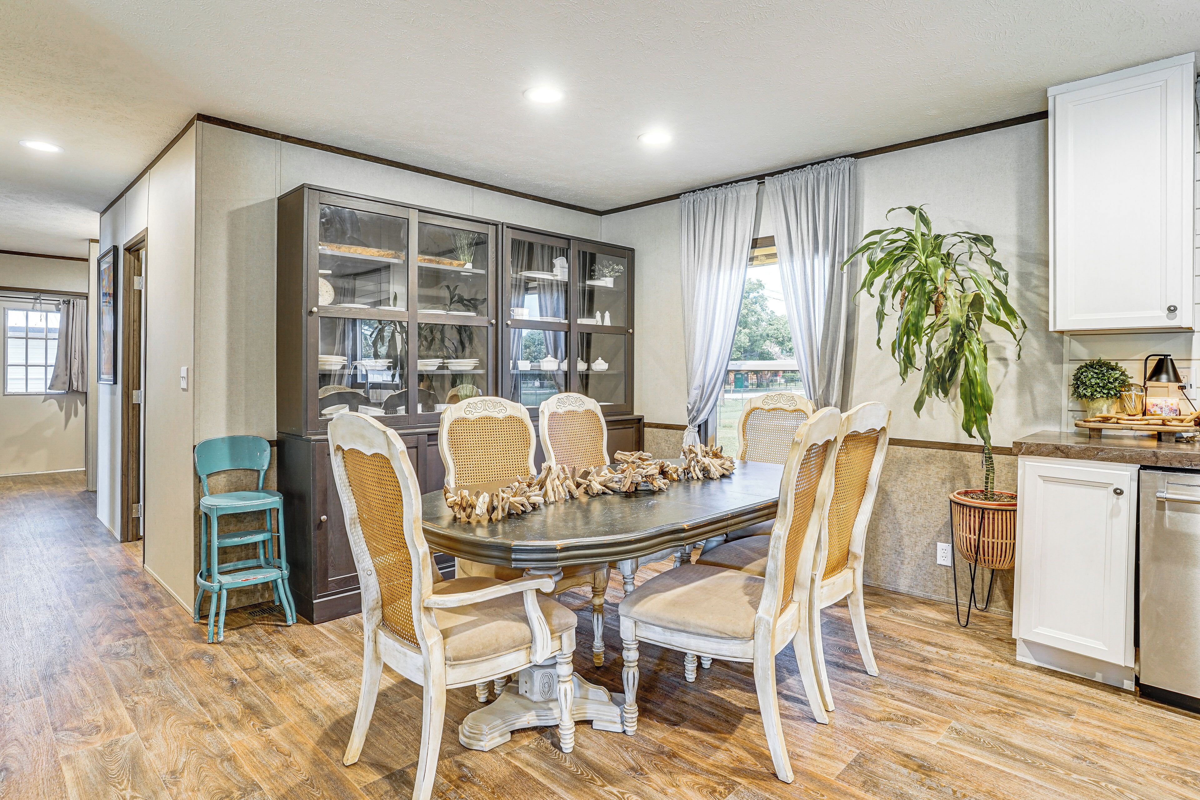 A dining area with a wooden table, six chairs, and a large cabinet with glass doors.