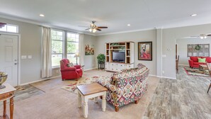 A spacious living room with a large sofa, a red armchair, and a television on a wooden cabinet. - 10 Mi to Aztec Ruins: Family Home w/ Large Yard! (Aztec)