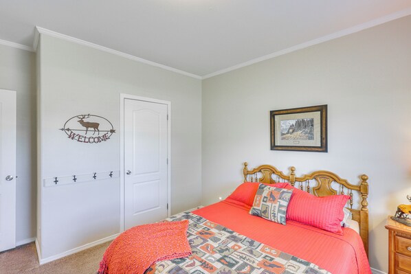 A bedroom with a bed, a door with a welcome sign, a framed picture on the wall, and a nightstand with a lamp. - 10 Mi to Aztec Ruins: Family Home w/ Large Yard! (Aztec)