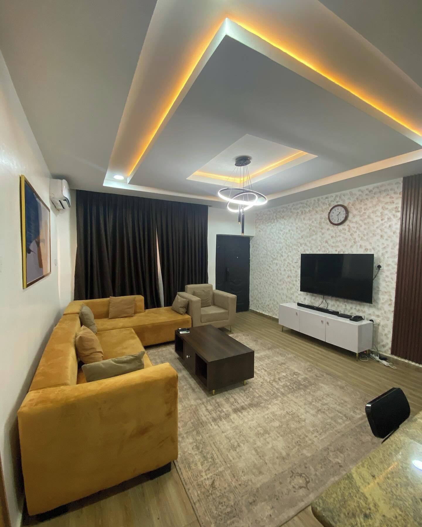 A modern living room with a sectional sofa, a coffee table, a TV, and a patterned wall.