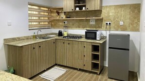 Eine kleine Küche mit Holzausstattung, einem Gasherd, einer Mikrowelle und einem Kühlschrank.