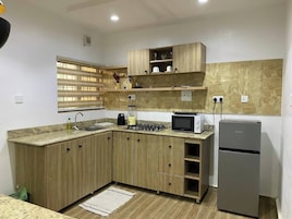 Uma cozinha compacta com armários de madeira, fogão a gás, micro-ondas e geladeira.