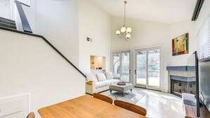 A modern living room with a wooden dining table, a sofa, and a fireplace. - Pool & Trail Access On-site: Modern Austin Condo! (Austin)