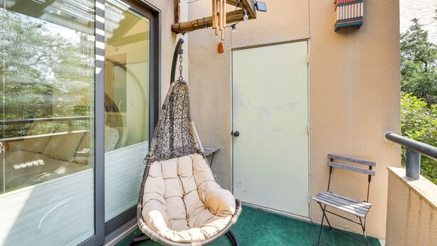 A balcony with a hanging chair, a small bench, and a door. - Pool & Trail Access On-site: Modern Austin Condo! (Austin)