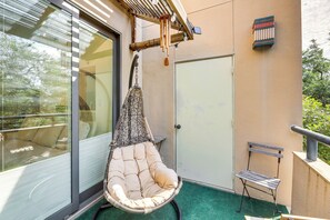 A balcony with a hanging chair, a small bench, and a door. - Pool & Trail Access On-site: Modern Austin Condo! (Austin)