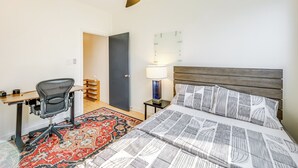 A hotel room with a bed, a desk, a chair, a lamp, and a door. - Pool & Trail Access On-site: Modern Austin Condo! (Austin)