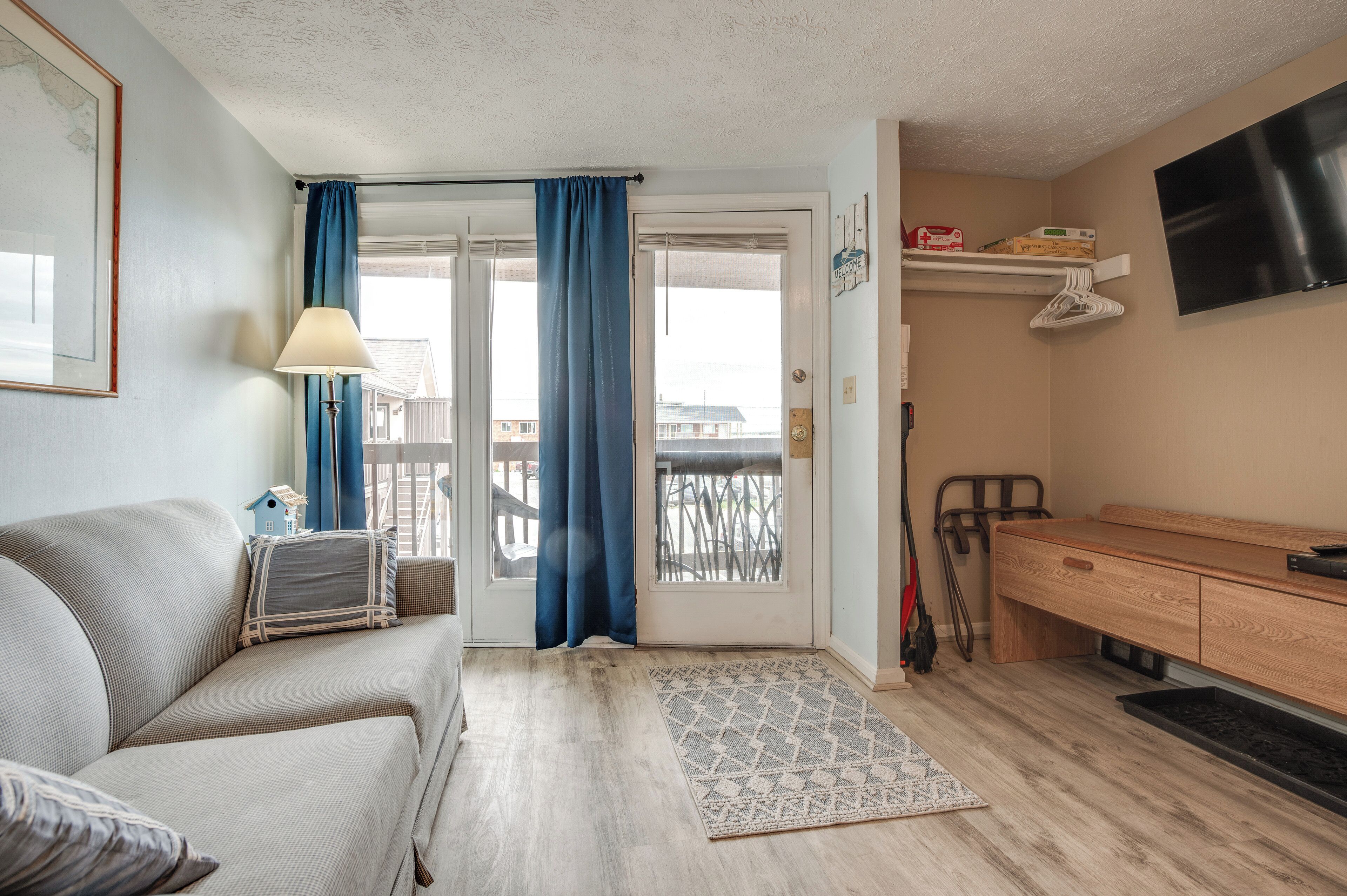 A room with a sofa, a wooden cabinet, a TV, and a balcony with a railing.