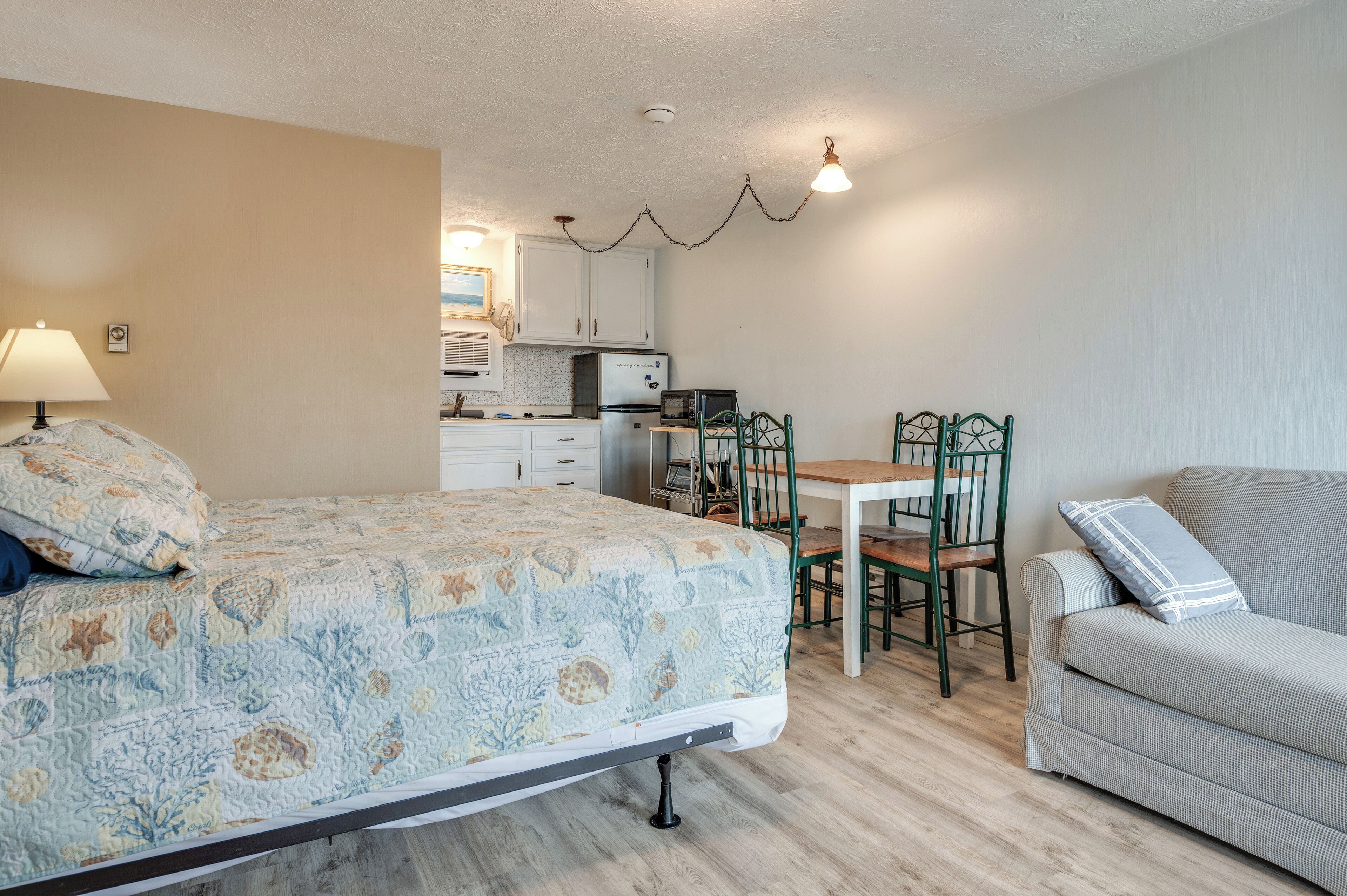 A bedroom with a bed, a desk, a chair, and a sofa.
