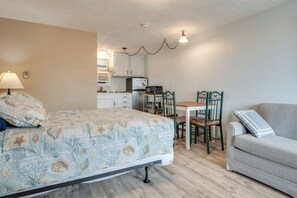 A bedroom with a bed, a desk, a chair, and a sofa.