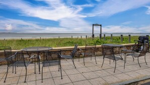 An outdoor patio with metal chairs and tables, overlooking a beach and the ocean. - Beachfront Unit 17 Fall Escape by the Ocean! (Old Orchard Beach)