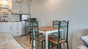 A compact kitchen with white cabinets, a microwave, and a refrigerator. There is a dining table with four chairs. - Beachfront Unit 17 Fall Escape by the Ocean! (Old Orchard Beach)