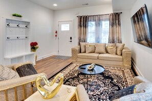 Una sala de estar con un sofá color beige, un tapete estampado y una pequeña mesa redonda.