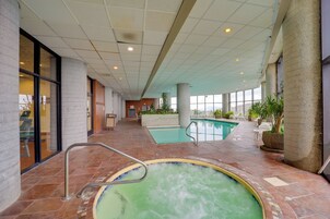 Una piscina interior con suelo de baldosas y una pequeña zona de hidromasaje.