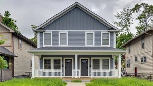 Een huis met twee verdiepingen, een veranda, een centrale deur en een kleine voortuin.