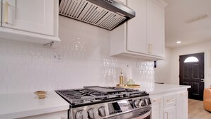 Een moderne keuken met witte kasten, een roestvrijstalen fornuis en een backsplash van hexagontegels.