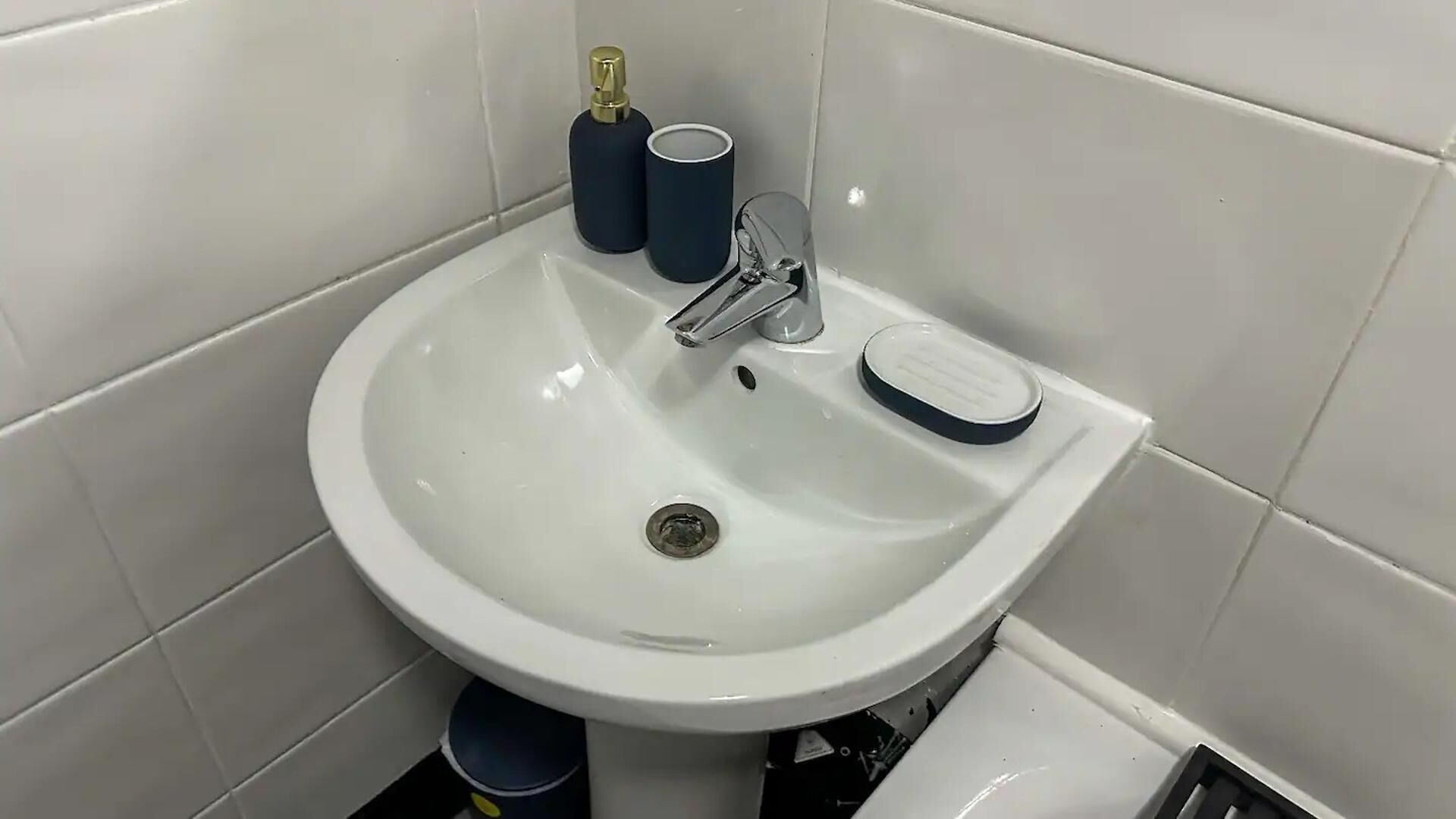 Een wit badkamermeubel met een chromen kraan, een zeepdispenser en een zeepstaafje.