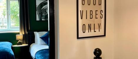 A hotel room with two beds, a framed motivational quote on the wall, and a view of greenery outside.