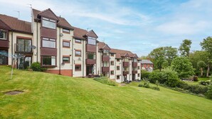A row of modern apartment buildings with a sloped roof, satellite dishes, and a well-maintained lawn. - Host Stay The Fairways (Stanley)