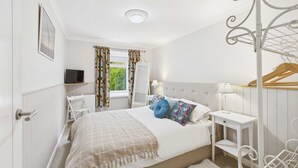 A bedroom with a bed, bedside table, lamp, TV, and a window with curtains. - Host Stay The Fairways (Stanley)