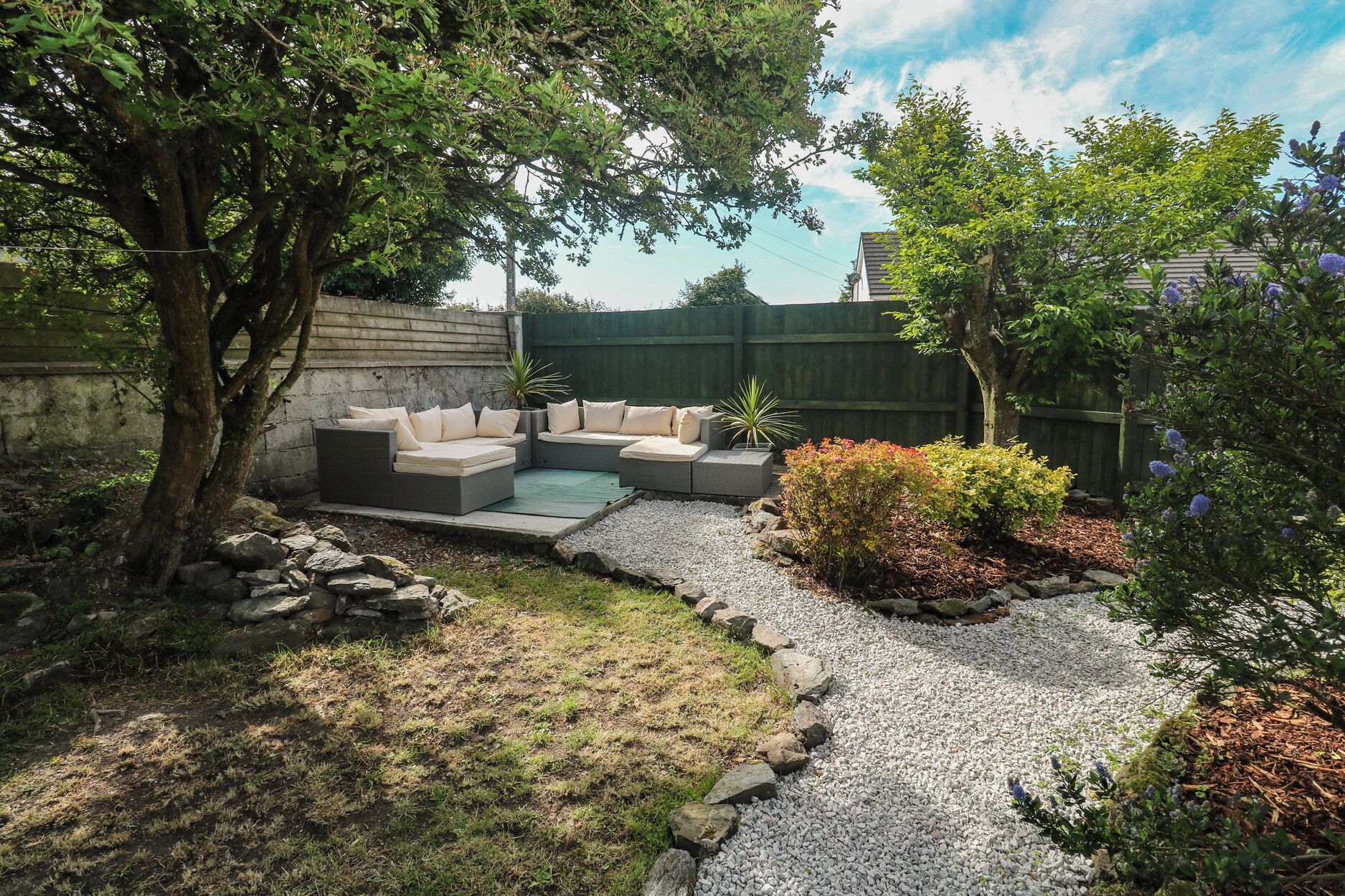 A backyard with a built-in seating area, a small garden, and a gravel path.