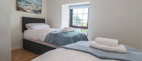 Un dormitorio con dos camas, una ventana con vistas a zonas verdes y un cuadro en la pared.