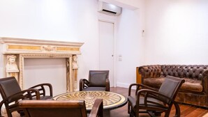 Une pièce avec une table ronde, quatre chaises, une cheminée et un canapé en cuir.