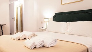 Une chambre d’hôtel avec un lit, deux serviettes enroulées, une table de chevet avec une lampe et un tableau encadré au mur.