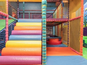 A multi-level indoor play area with colorful padded steps and netted walls. - Moonlit Skylight - Billing Aquadrome (Northampton)