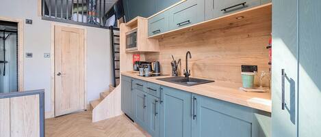 A modern kitchen with wooden cabinets, a countertop, and a built-in microwave.