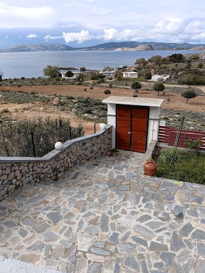 Una escalera de piedra que lleva a una puerta de madera, con vistas a un paisaje costero y montañas distantes.
