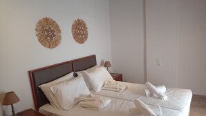 Un lit bien fait, avec du linge de lit et des serviettes blanches, deux tables de chevet avec des lampes et deux éléments de décoration murale.