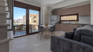Una cocina moderna con una pared de acento de piedra, un comedor con una mesa redonda y sillas, y un sofá gris.