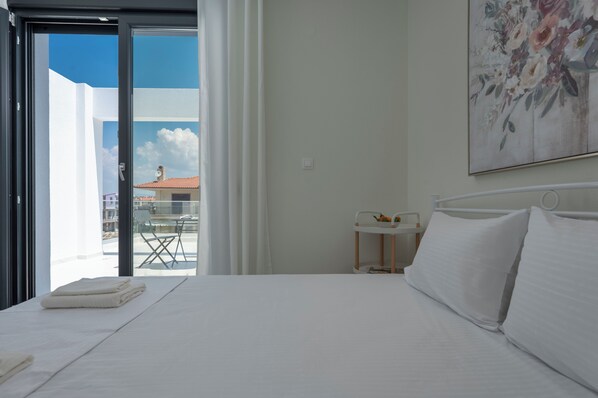 Una habitación de hotel con cama, una mesita de noche, una ventana con vistas al exterior y un cuadro en la pared.