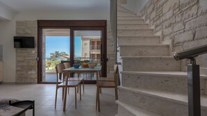 Una sala de estar moderna con comedor, una escalera y vistas al exterior.