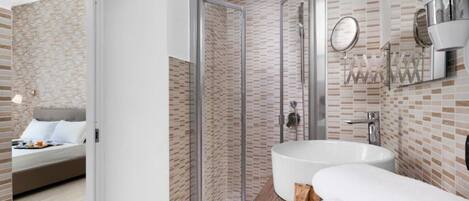 Un baño moderno con ducha de vidrio, lavamanos grande y espejo.