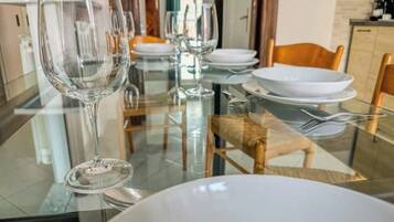 Una tavola da pranzo apparecchiata con bicchieri trasparenti, piatti bianchi e una ciotola per un pasto.