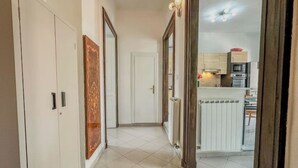 A hallway leading to a kitchen with white cabinets and a tiled floor. - Antique Heritage Suite in Porta Nuova (Torino)