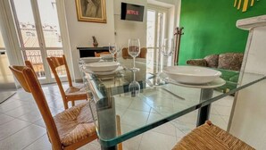 A dining area with a glass table, chairs, and a green wall. - Antique Heritage Suite in Porta Nuova (Torino)