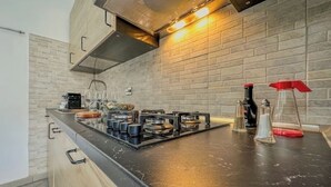 A modern kitchen with a black countertop, stainless steel appliances, and a brick backsplash. - Antique Heritage Suite in Porta Nuova (Torino)