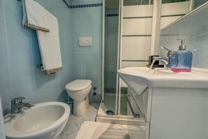 Un baño con bidé, inodoro y lavamanos.