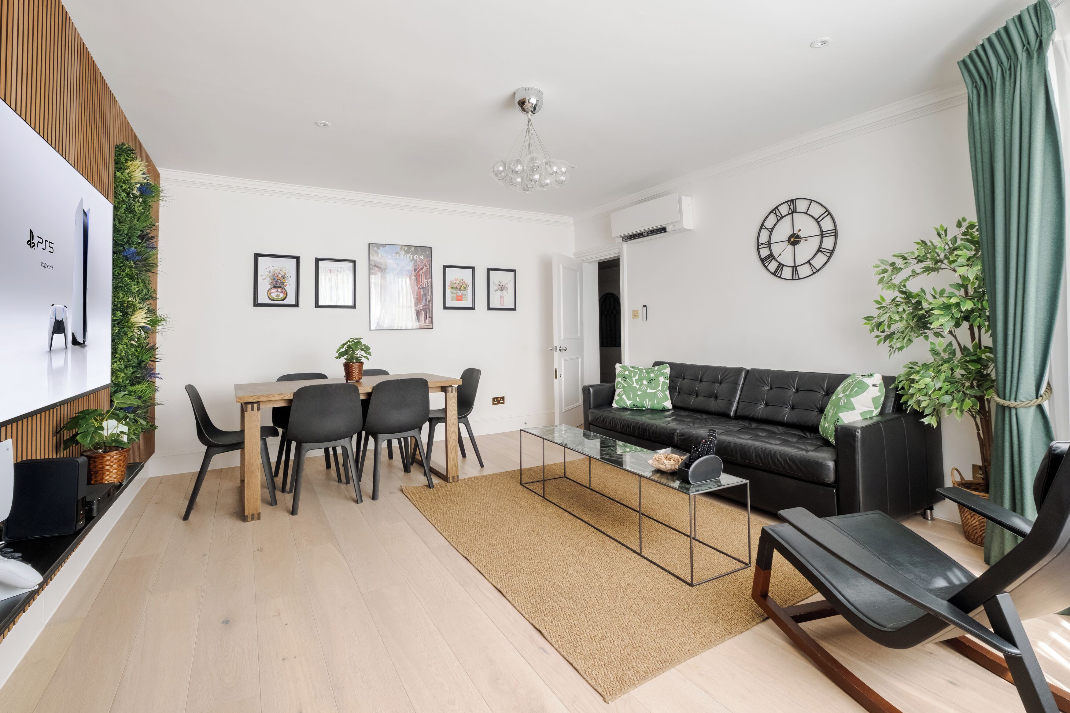 Een moderne woonkamer met een eethoek, een zwarte leren bank, een glazen salontafel en een eettafel met stoelen.