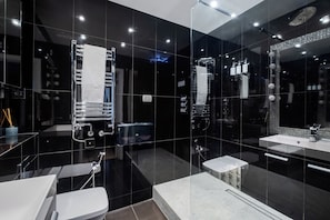 A modern bathroom with a glass-enclosed shower, a white sink, and a large mirror.