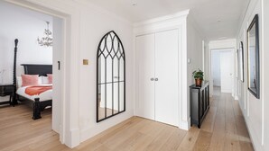 Un couloir comprenant un lit, une porte décorative et une console sur laquelle est posée une plante.