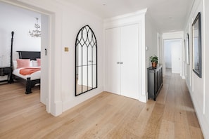 A hallway with a bed, a decorative door, and a console table with a plant.