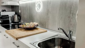 A modern kitchen with stainless steel appliances, a wooden cutting board with food, and a sink. - Loft Design + Garage and Fitness Area (Torino)