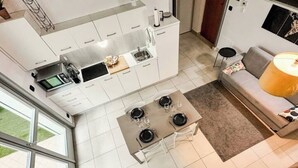 A modern kitchen with white cabinets, a dining table set for four, and a large window providing natural light. - Loft Design + Garage and Fitness Area (Torino)